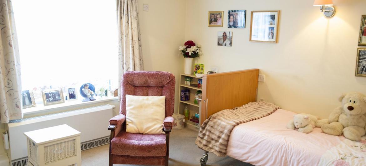 A pretty bedroom with soft toys and comfy chair at Time Court Residential and Nursing Home.