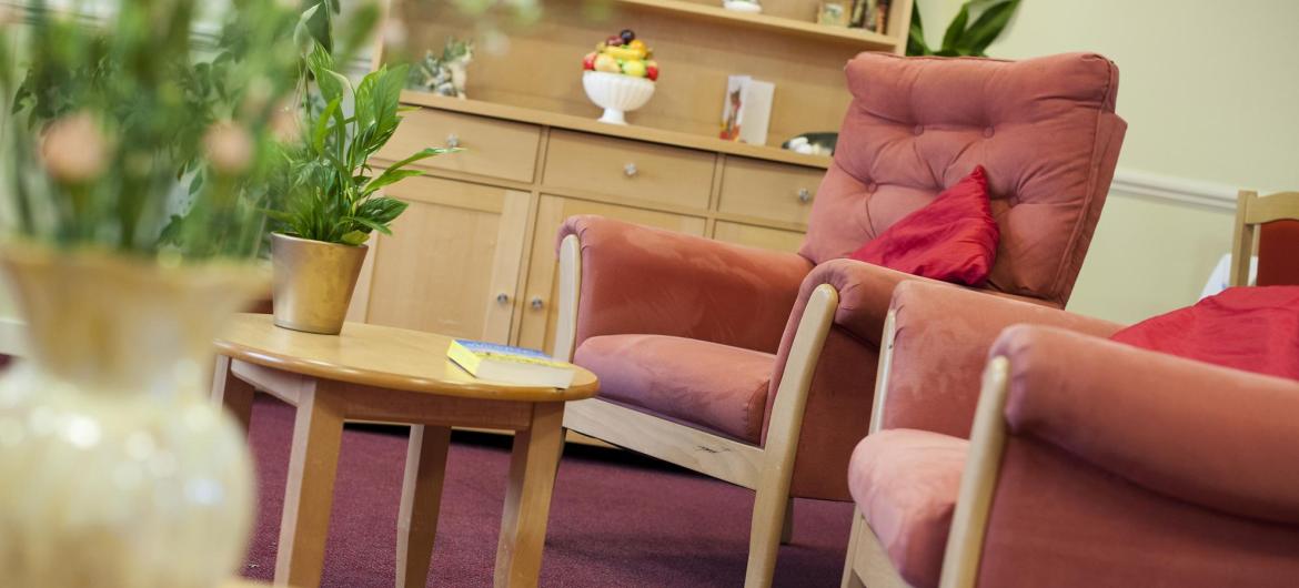 Comfy seats, flowers and a wooden dresser in the lounge at Time Court Residential and Nursing Home.