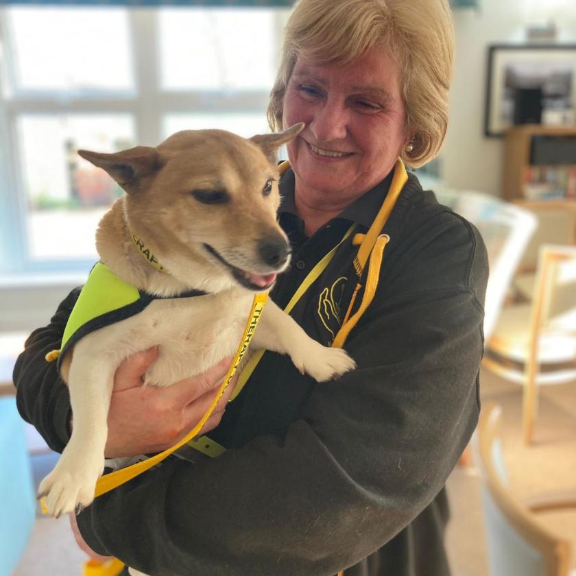 Jean a volunteer holding therapy dog Flo in her arms