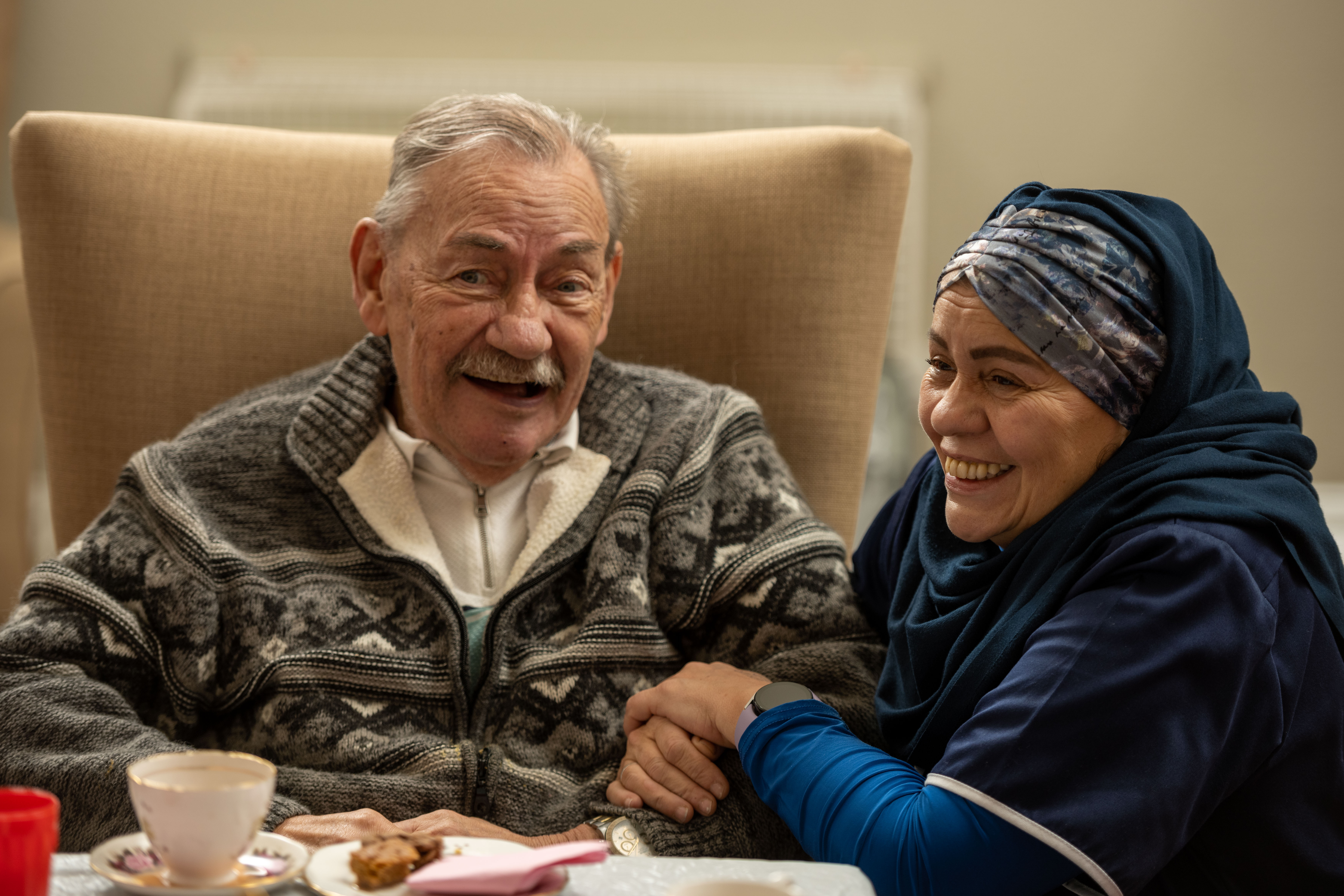 Elderly gentleman and nurse sit and smile together