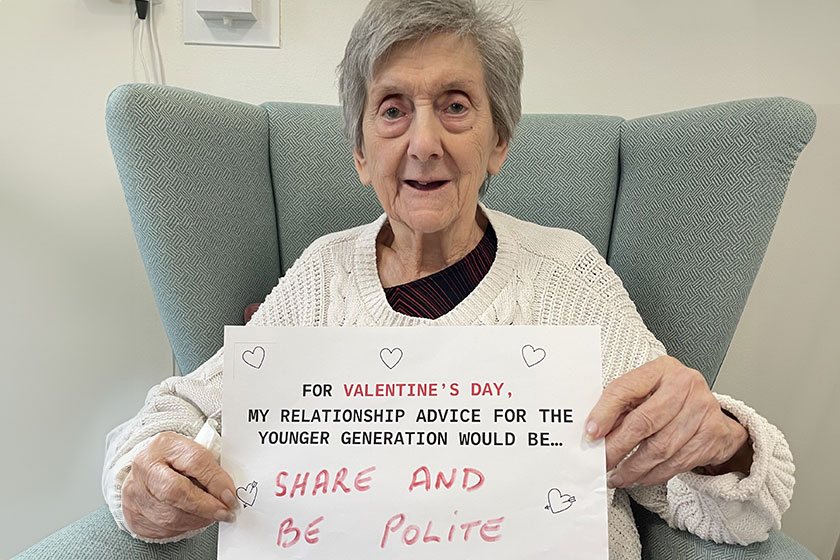 A resident holding a sign saying For Valentine's Day, my relationship advice for the younger generation would be... share and be polite