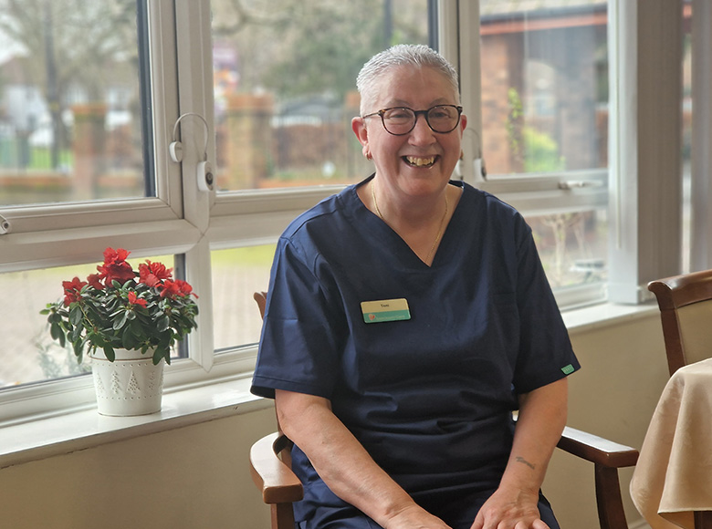 Sanctuary staff member Toni sat smiling in a chair at Lammas House Care Home