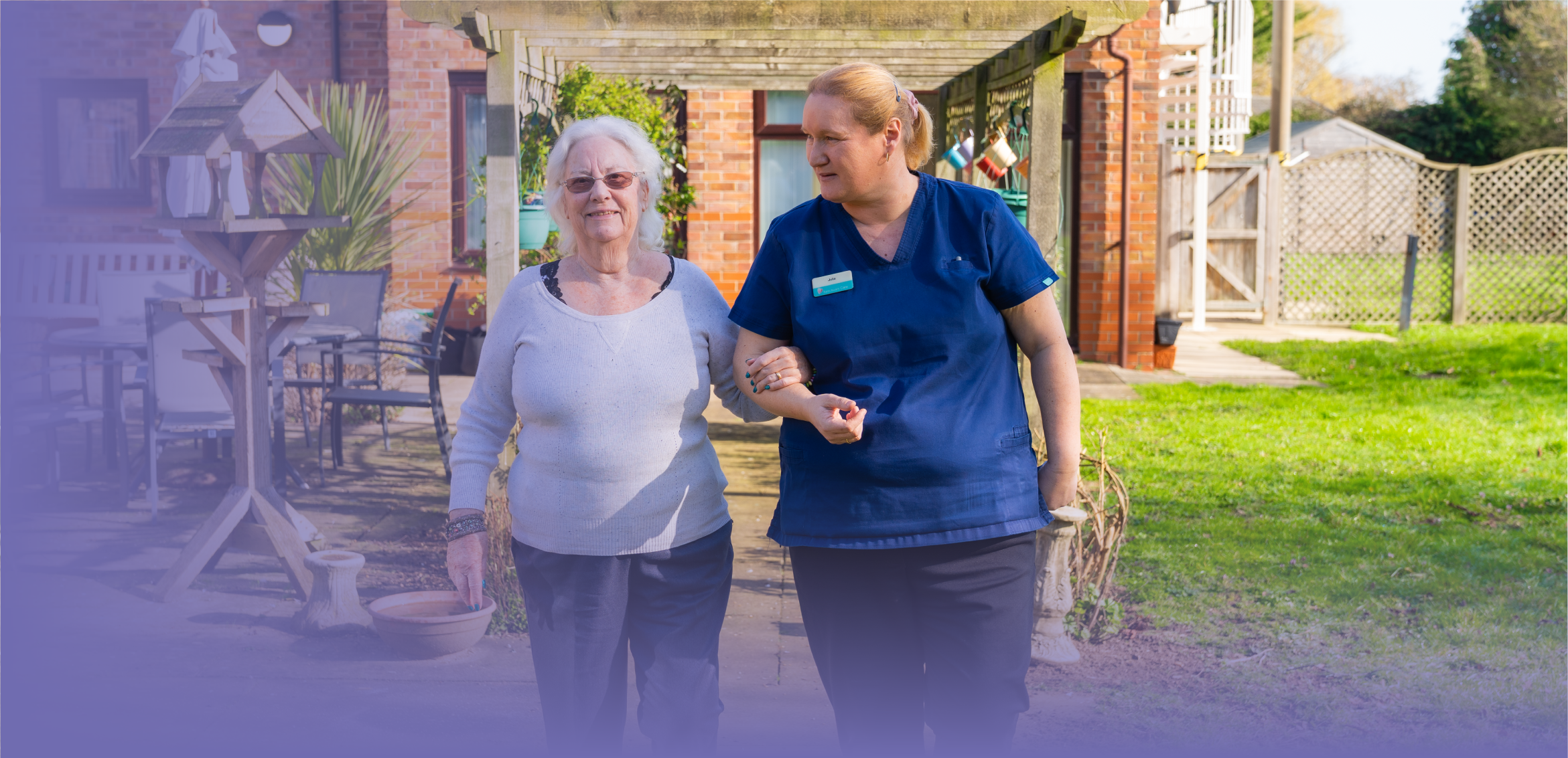ID31 Jobs management careers - Build a career that grows with you care colleague walking arm in arm with an older person along a garden path outside a care home.