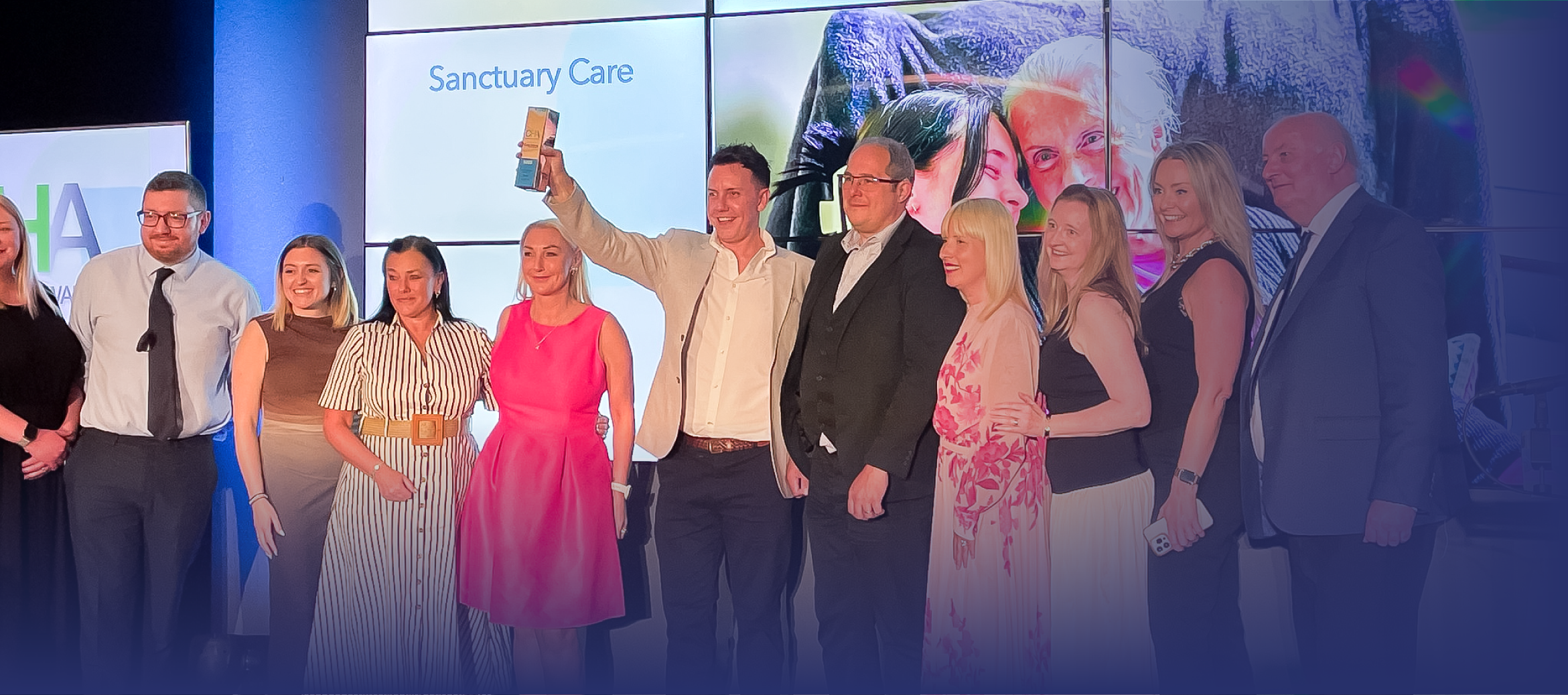 ID32 Jobs management careers - Systems that support your role A group of people standing on a stage during an awards ceremony, with one person holding up a trophy.