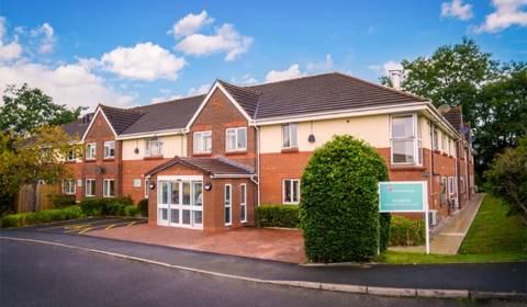 Exterior of a red brick building with white accents. In the foreground is a sign that states 'Ivydene Residential and Nursing Home'
