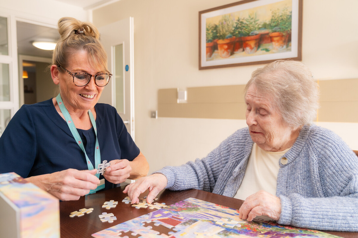 Care team member and resident completing a jigsaw puzzle together in a care home