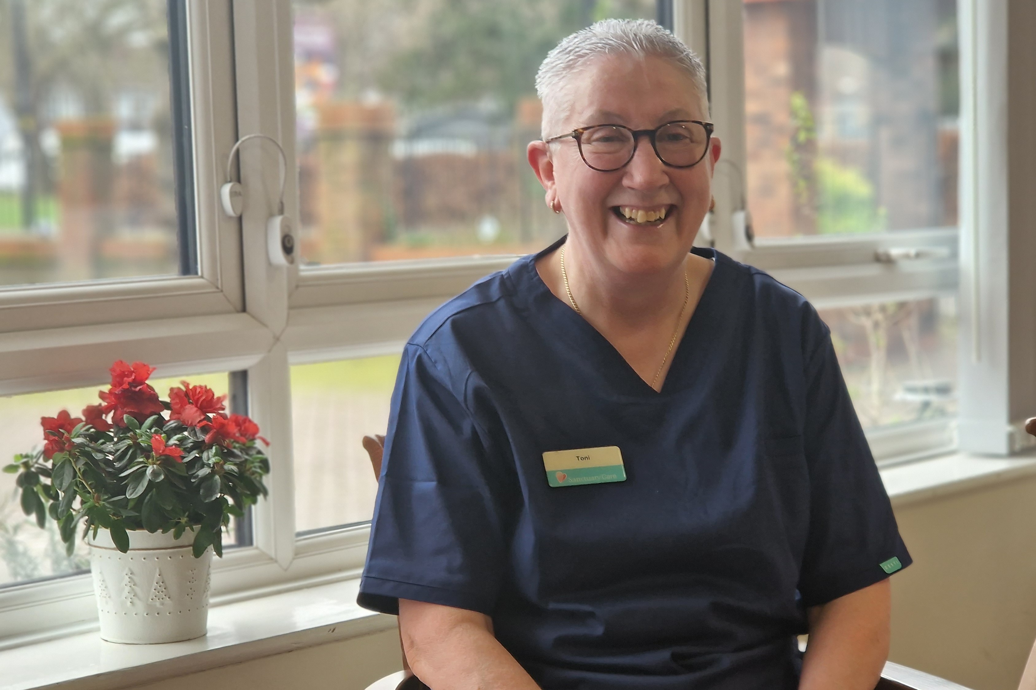 Staff member Toni Carrigan smiling in front of a window 
