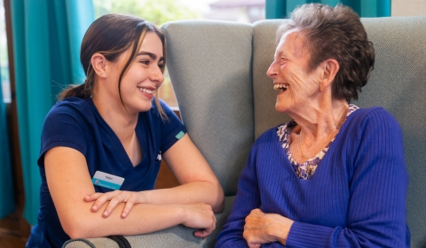 A carer and resident laughing and smiling together