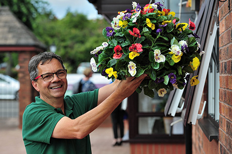 A staff member assembling a vibrant flower basket of pansies