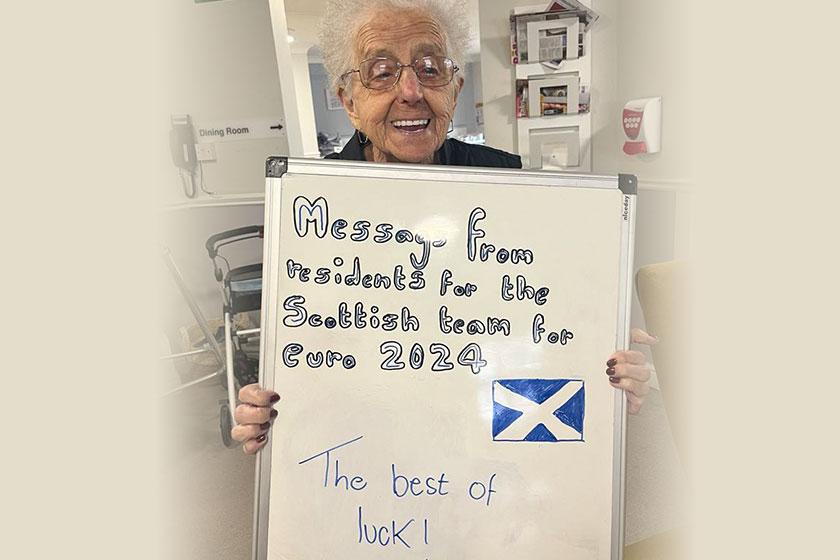 Care home residents wish Scotland's national football team luck ahead of the Euros Resident Catherine Meek holding a board wishing the Scotland football team luck in their game against Germary