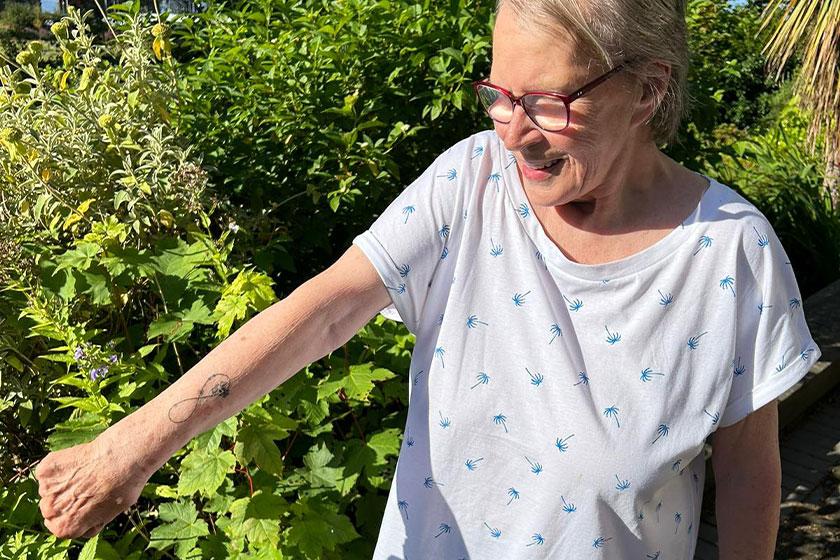 Tricia outside Bridge View House Care Home in Dundee, her home, proudly showing off her new tattoo Resident Tricia, 82, Fulfils Lifelong Dream with First Tattoo