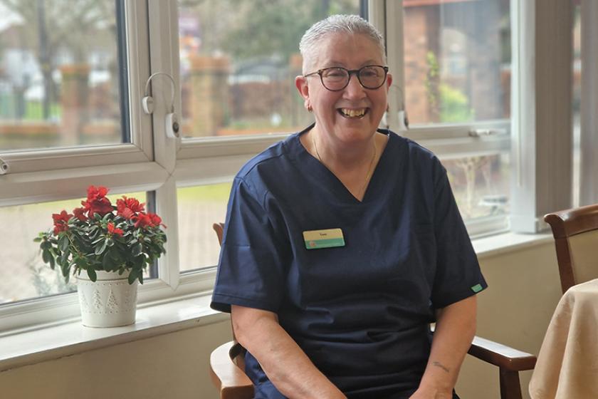 Sanctuary staff member Toni sat smiling in a chair at Lammas House Care Home
