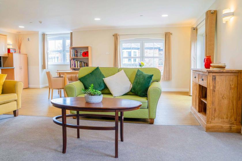 A bright, cosy lounge with comfy seating, natural light, and a homely feel designed for comfort, relaxation, and community.