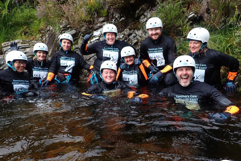 The team from Sanctuary Care's Scotland East smile for the camera in the water during their canyoning adventure