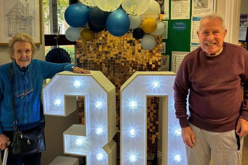 Residents smile for the camera in from of illuminated 30 sign