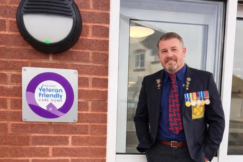 Home Manager stood next to Veteran friendly care home logo