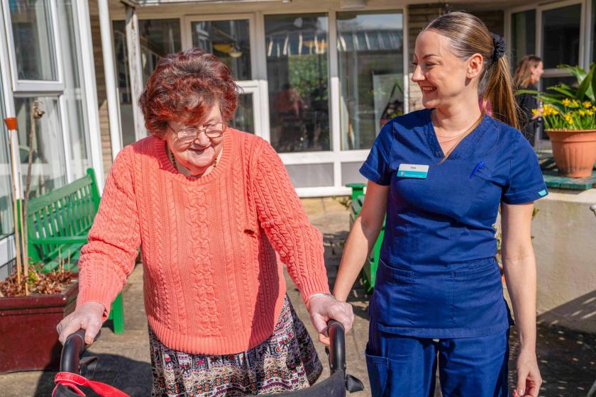 A resident and staff member walking together in the garden