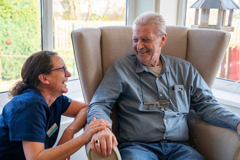 A care worker and resident sat having a conversation and smiling