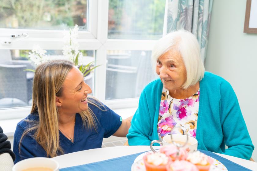 A care worker and resident chatting over a cup of tea