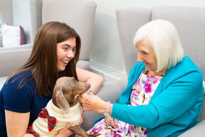 Staff and Resident smiling with puppy