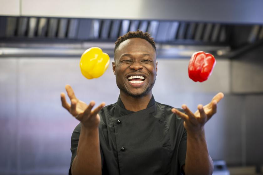 A sanctuary care chef in the kitchen juggling with two peppers