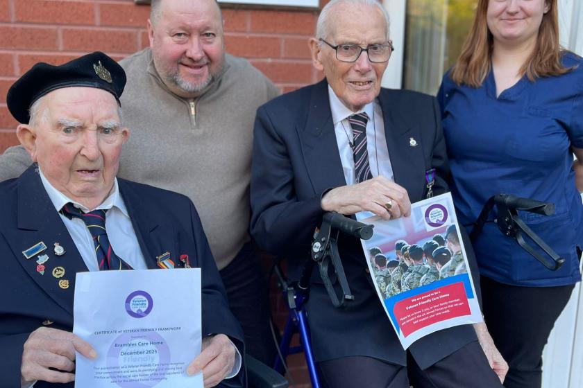 two veterans holding certificates with staff