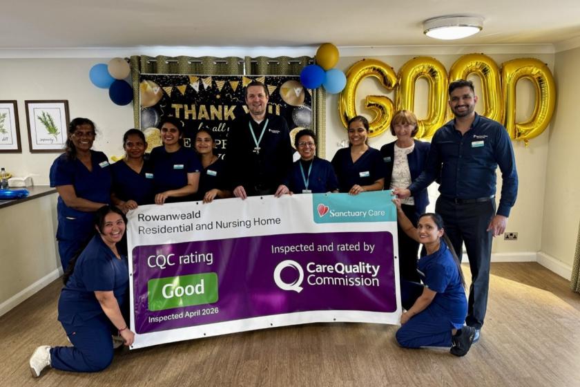 Group of staff celebrating a "Good" CQC rating with large gold balloons