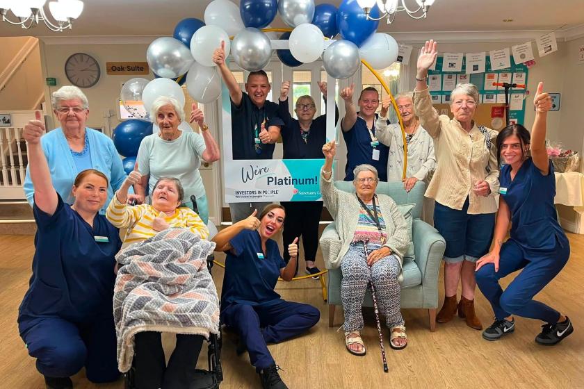Residents and team members at a care home celebrating the platinum investors in people award with balloons and banners