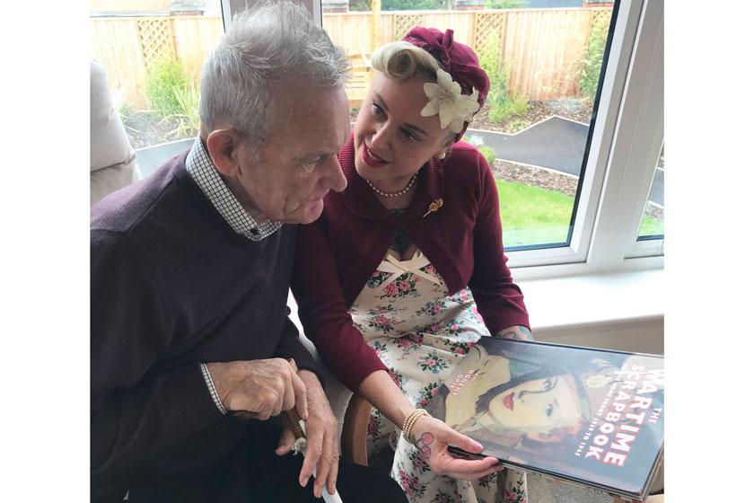 A staff member in roaring forties fancy dress speaking to a resident.