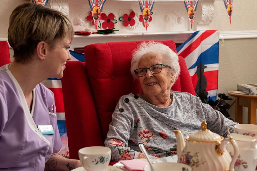 An elderly woman talking to a care home worker in a seat at the Redannick and Trevern care homes in Cornwall.