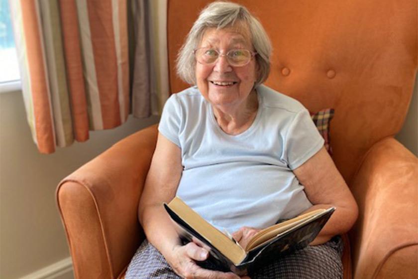 Sanctuary Care resident June Watson holding a book