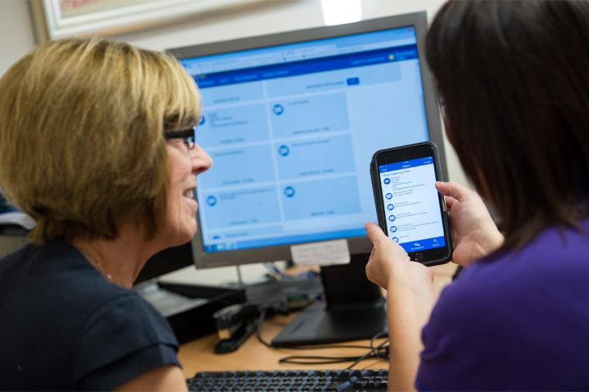 Sanctuary staff look at the Kradle app on a mobile and PC.