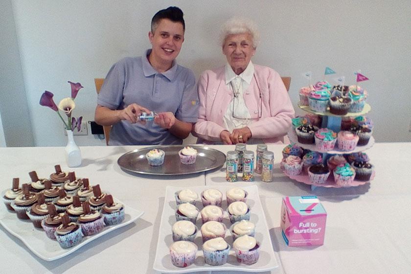A member of staff and resident show off the display of cakes baked in support of the Alzheimer's Society.