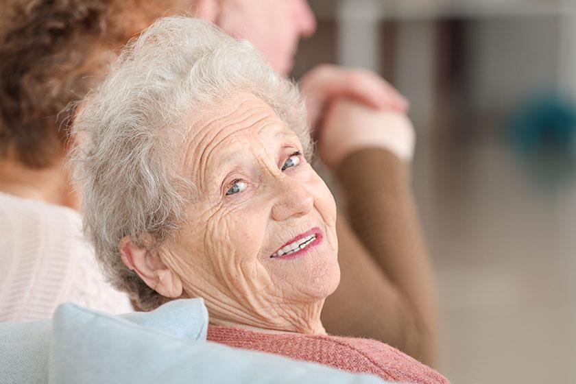 A happy care home resident smiles at the camera