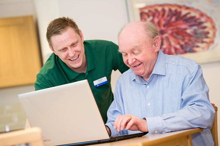 Digital Buddies assist an older man with a computer.