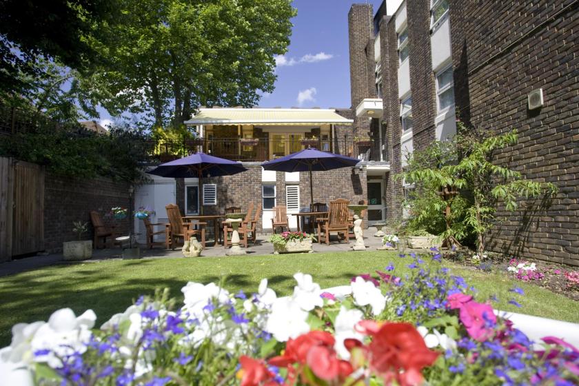 Tables, chairs and umbrellas in the pretty back garden at Forest Dene Residential Care Home.