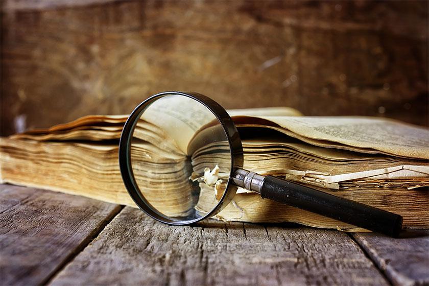 Image showing a magnifying glass next to an old, withered book.