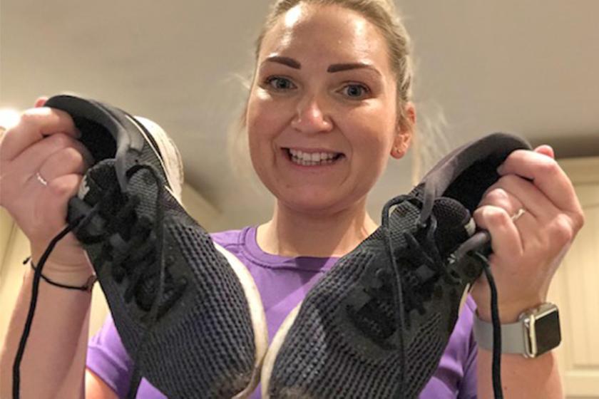 A female holds up a pair of trainers. as she prepares for  a charity run