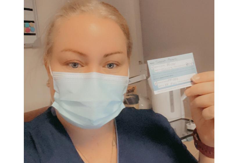 Deputy manager and nurse Sheena Adams wears a mask whilst showing her Covid vaccination card