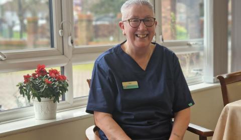 Staff member Toni Carrigan seated and smiling in front of a window