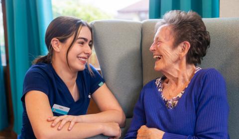 A care worker and a resident having a conversation and laughing together