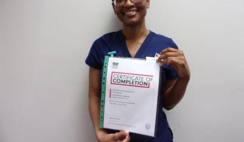Roshell holding a certificate of completion and smiling