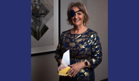 Sheila holding an award and smiling