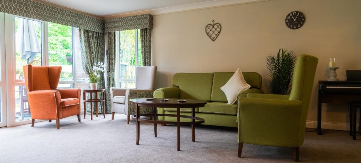Two armchairs and a sofa around a coffee table in a well lit room next to a large window
