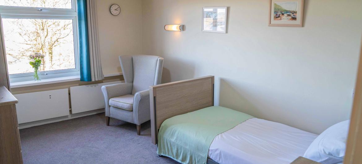 Interior of a well light bedroom with a single bed and a high-backed armchair