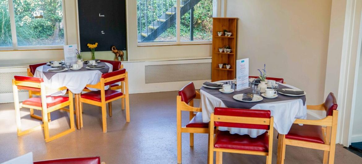 A cluster of round wooden dining tables with wooden and leather chairs 