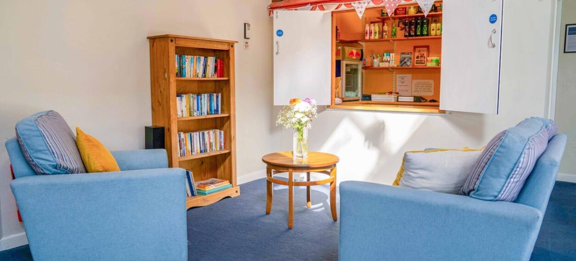 A blue sofa and matching armchair facing a small shop.