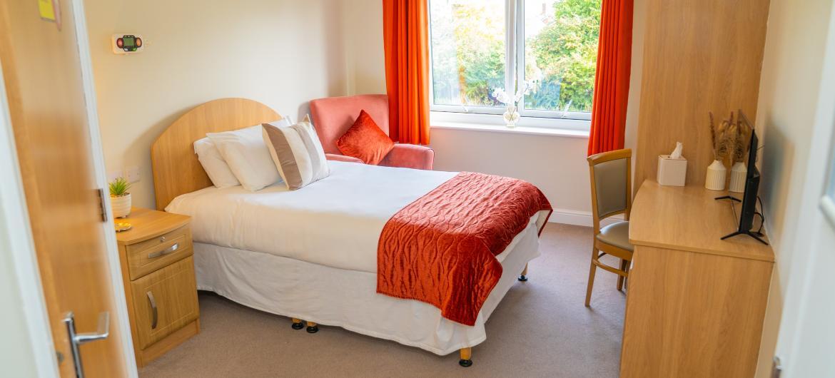 A well lit bedroom with a large window and a comfortable bed