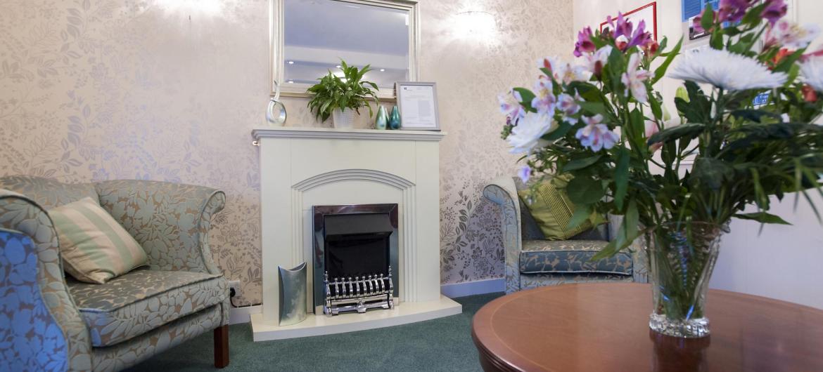 The Regent Residential Care Home reception area with comfy chairs, flowers and an open fire.