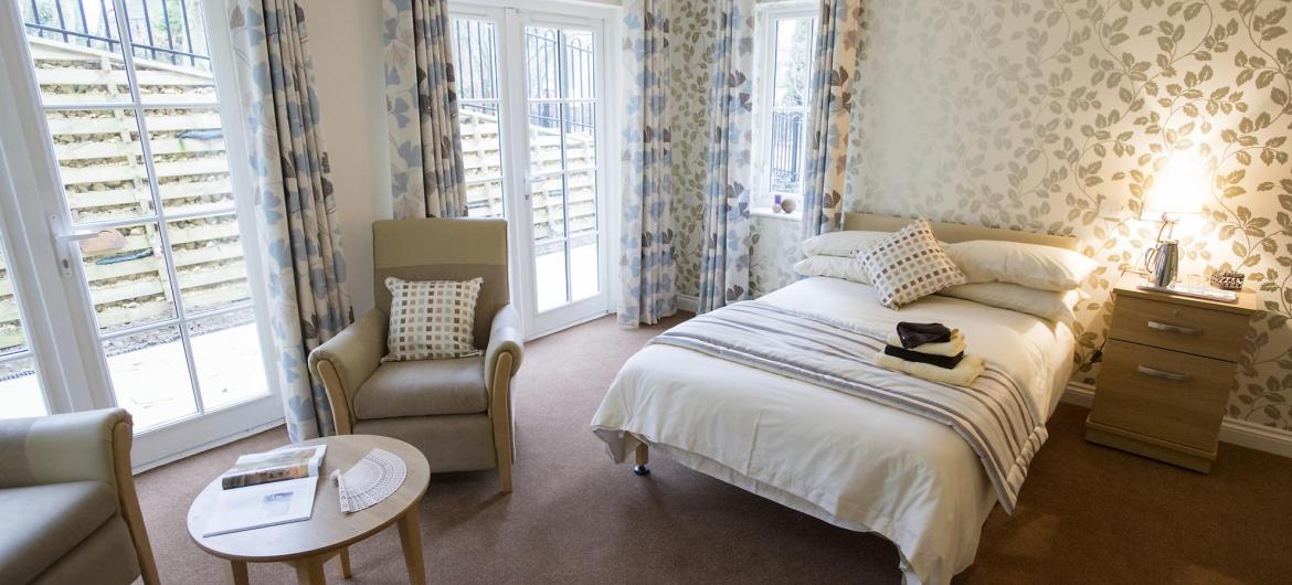The designer-styled bedroom at Iffley Residential and Nursing Home has full length windows and soft lighting.